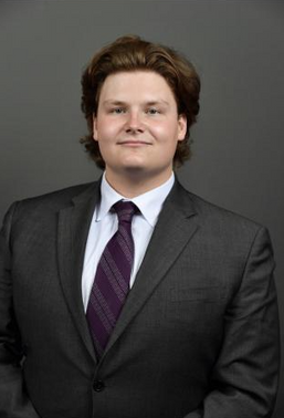 Christopher posing in a suit in front of backdrop for a professional headshot